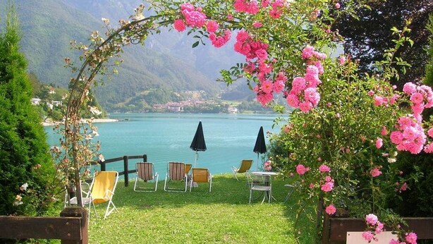 Eine private Villa mit Seeblick und Bergblick. Draußen stehen Stühle und Sonnenschirme bereit.