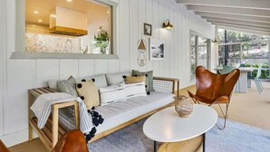 Uma sala de estar moderna com um sofá, uma mesa redonda e uma janela ampla.