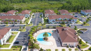 A residential complex with multiple two-story houses, a central swimming pool, and a parking area. - Moana's Hut Miles From World's Best Theme Parks! (Kissimmee)