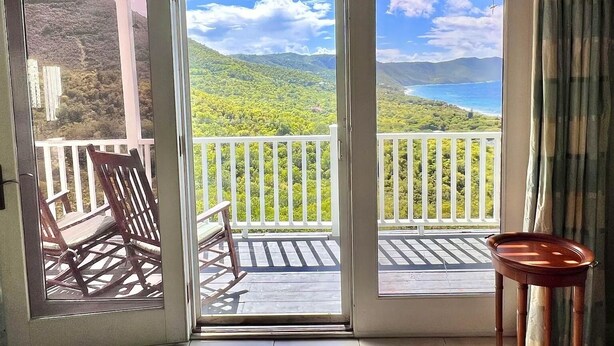 Een balkon met uitzicht op een bergachtig landschap en een waterpartij.