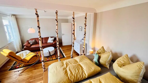 Ein Zimmer mit einem Bett, einem Schaukelstuhl, einer Couch und einem kleinen Tisch.