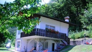 Ein zweistöckiges Haus mit einem Balkon, einem steinernen Bogen und einer kleinen Außen-Sitzgelegenheit mit Stühlen.