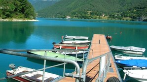 Ein Steg mit mehreren Booten, eine Holzpier und ein See, der von Bergen umgeben ist.