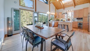 Una cocina amplia con armarios de madera, una isla grande y una zona de comedor con mesa y sillas de madera.