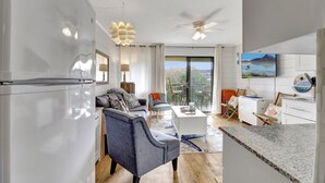 Una cocina moderna con refrigerador empotrado, un comedor con mesa y sillas, y un amplio ventanal con vistas al exterior.