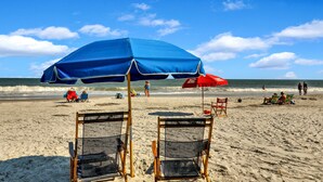 Una playa con dos sillas y una sombrilla azul.