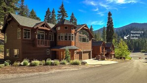 Heavenly's Boulder Lodge, ein großes Holzhaus mit zahlreichen Fenstern und einem Balkon, umgeben von Bäumen und Bergen.