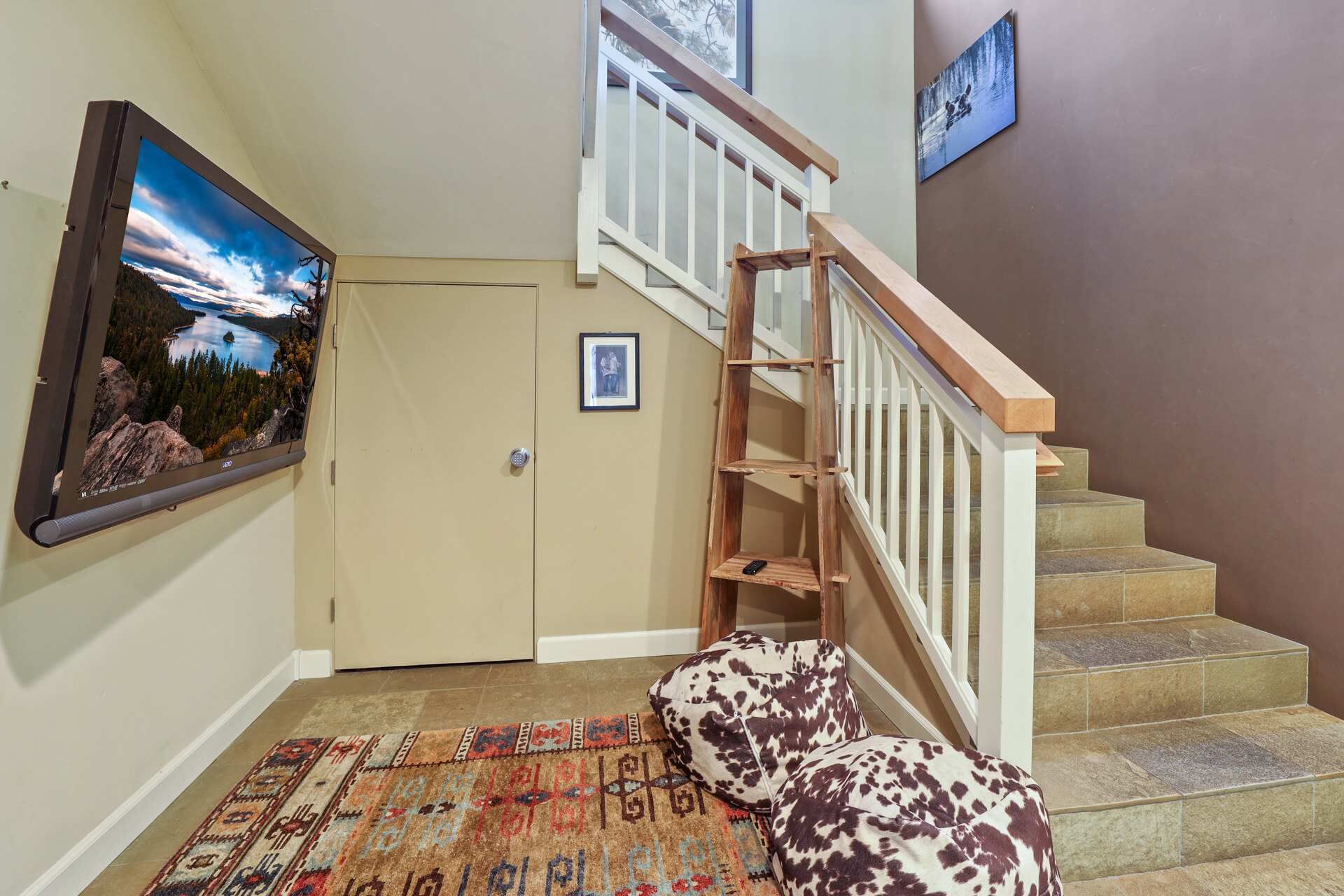 Un escalier avec une rampe en bois et des marches de couleur beige, un tableau encadré accroché au mur et un tapis à motifs sur le sol.