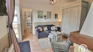 A living room with a sofa, a small table, a basket, and a wooden bench.