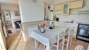 A kitchen with a dining table, chairs, a stove, and cabinets.
