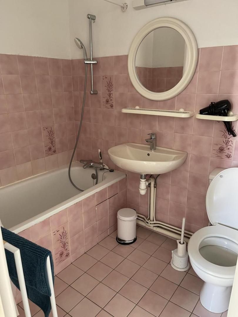 A bathroom with a bathtub, sink, toilet, and a mirror.