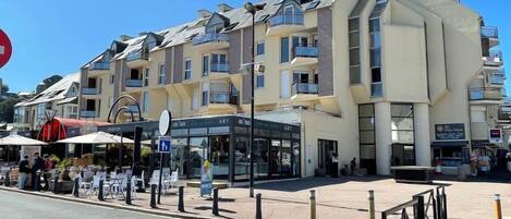Een hotel met meerdere verdiepingen, balkons, een overdekt terras en een heldere lucht.