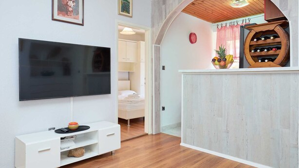 A modern living room with a flat-screen TV, a white entertainment unit, and a wooden wine rack.