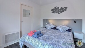 A bedroom with a bed, a bedside table, a wall decoration, and a radiator.