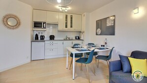 A compact kitchen with white cabinets, a microwave, and a dining area with a table and chairs.