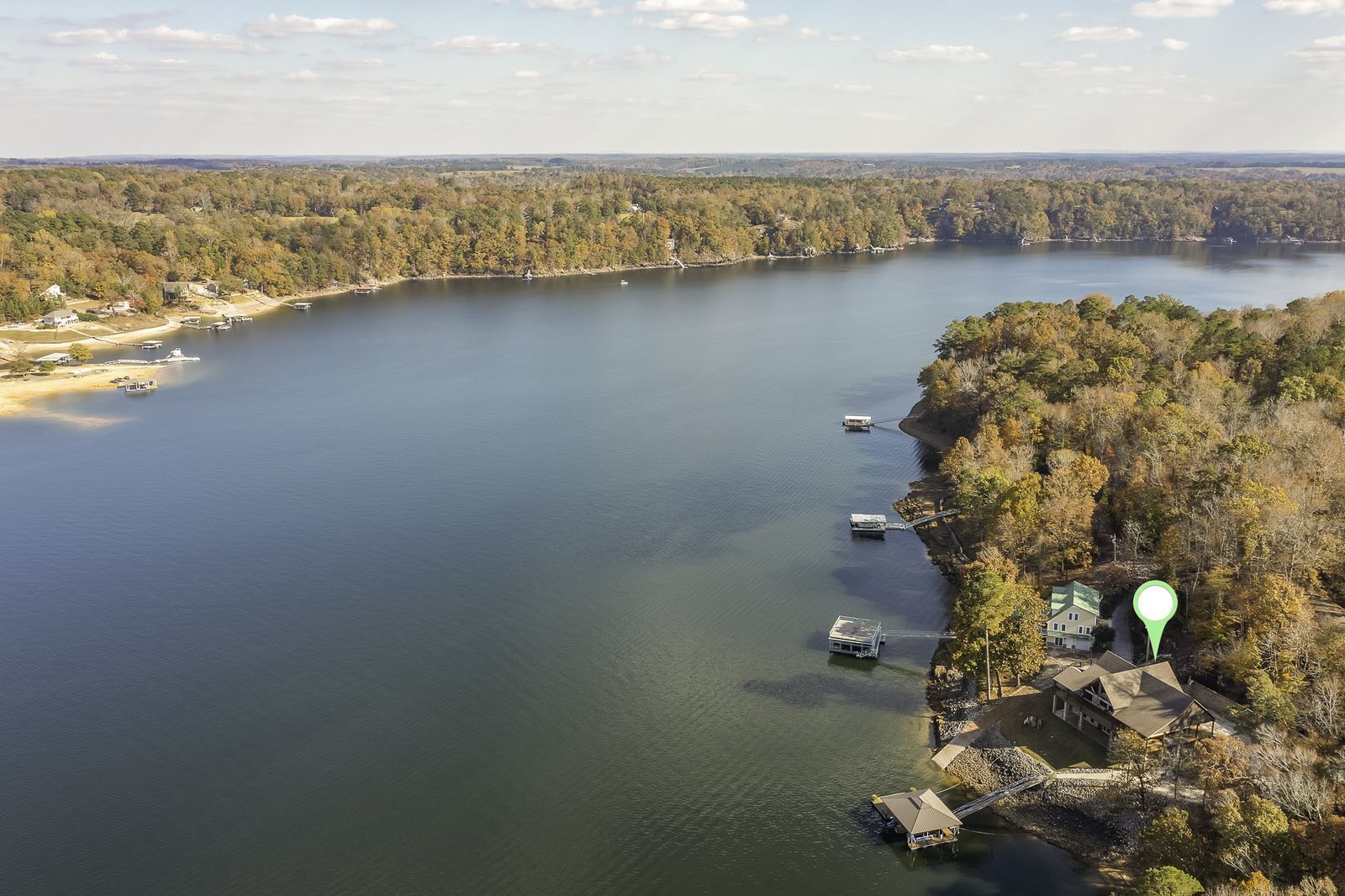An aerial view of a lake with boats, a dock, and a house on the shore.