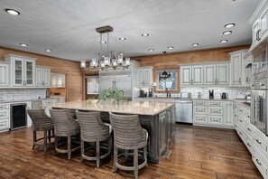 A spacious kitchen with a large island, wooden flooring, and white cabinetry.