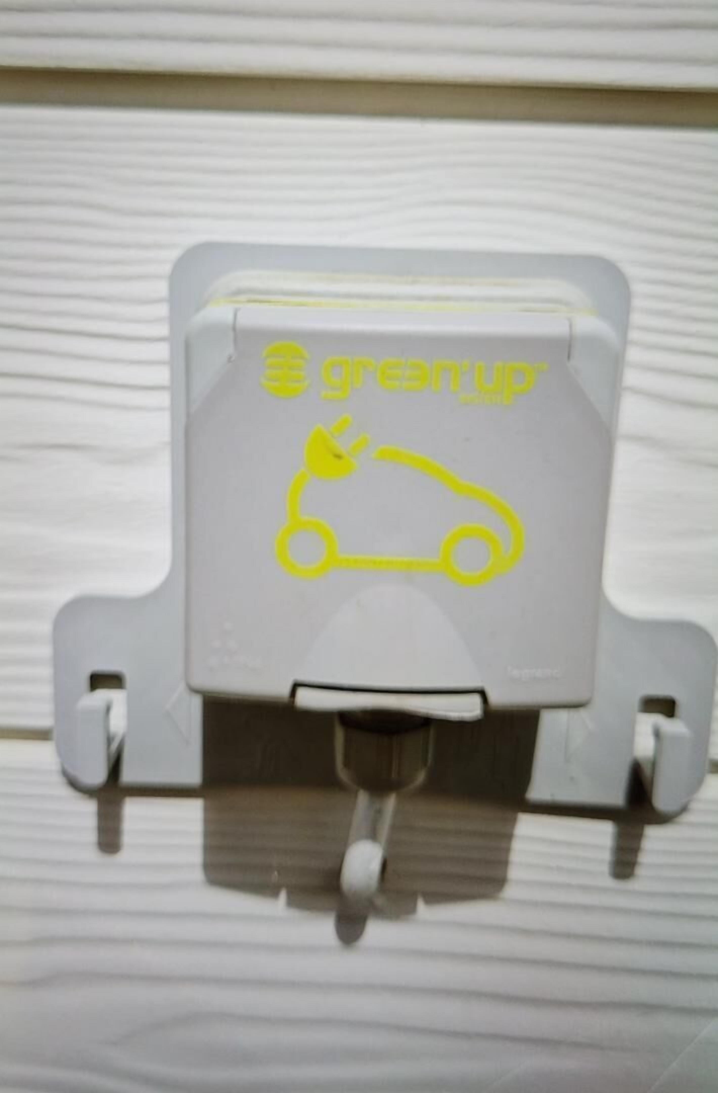 Een grijs object met een geel logo en tekst, mogelijk een bord of etiket.