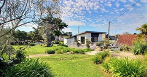 A residential property with a modern house, a well-maintained lawn, and surrounding greenery.
