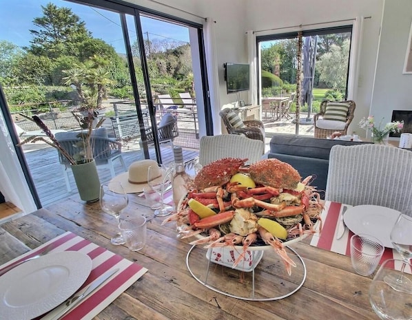A dining table with seafood, outdoor seating, and a view of the garden.