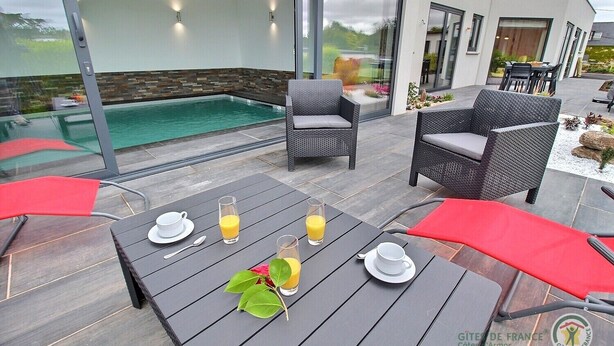A modern outdoor dining area with a pool, wicker furniture, and a view of the surrounding landscape. - La Roche Mignonne - Trebeurden (TREBEURDEN)