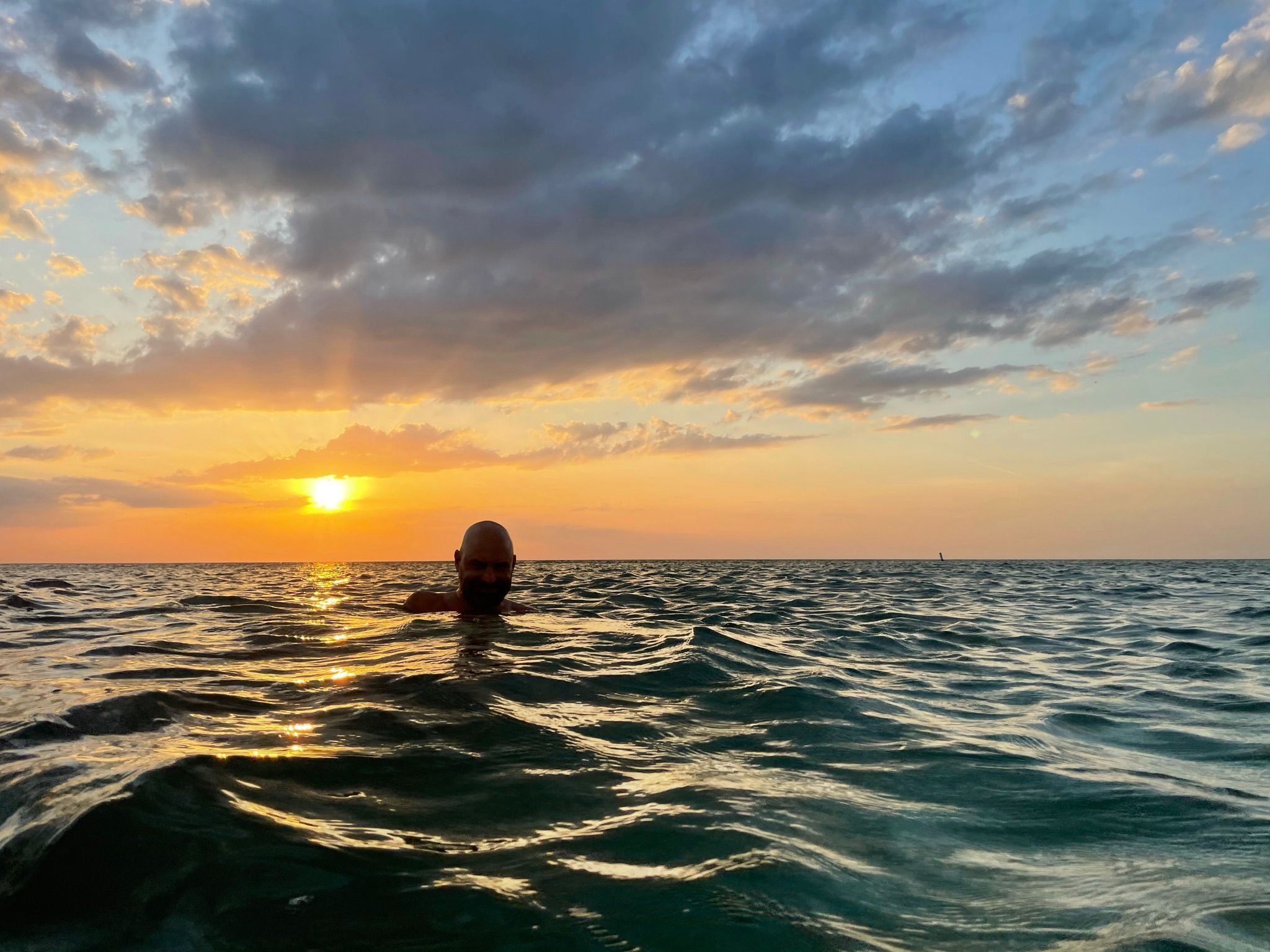 Iemand zwemt in de oceaan tijdens de zonsondergang.