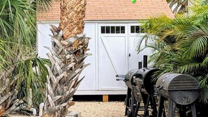 A backyard with a barbecue grill, a white shed, and a palm tree. - Family-friendly 2-bed, 2-bath ground-floor unit in Indian Rocks Beach. Sleeps eight with full kitchen, WiFi, smart TV, beach gear, and direct pool access. A comfortable, convenient base for sand days, sunsets, and easy coastal living (Indian Rocks Beach)