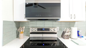 A kitchen with a built-in oven and microwave, a stovetop, and a ceiling fan. - Family-friendly 2-bed, 2-bath ground-floor unit in Indian Rocks Beach. Sleeps eight with full kitchen, WiFi, smart TV, beach gear, and direct pool access. A comfortable, convenient base for sand days, sunsets, and easy coastal living (Indian Rocks Beach)