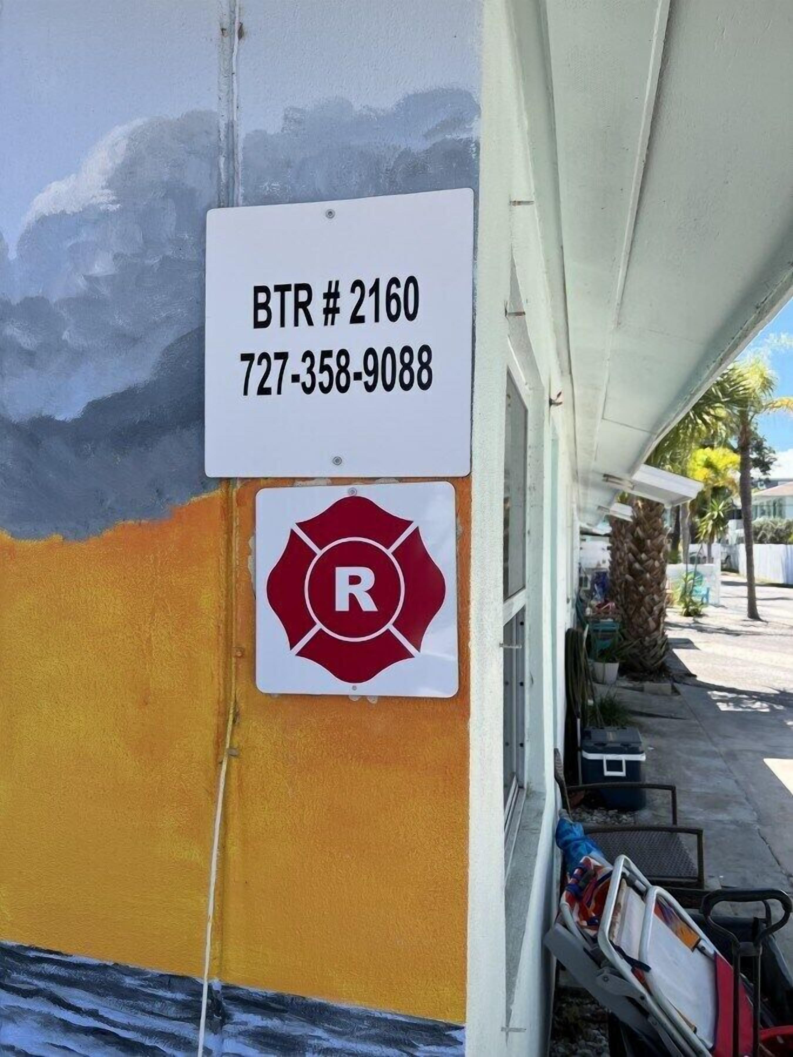 Un edificio con un mural, un letrero BTR #2160 y una señalización de estacionamiento con la letra 'R' en rojo.