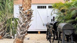 A backyard with a barbecue grill, a white shed, and a palm tree. - MySunsetView 6 Unit3 Studio+Pool 3min to Beach (Indian Rocks Beach)