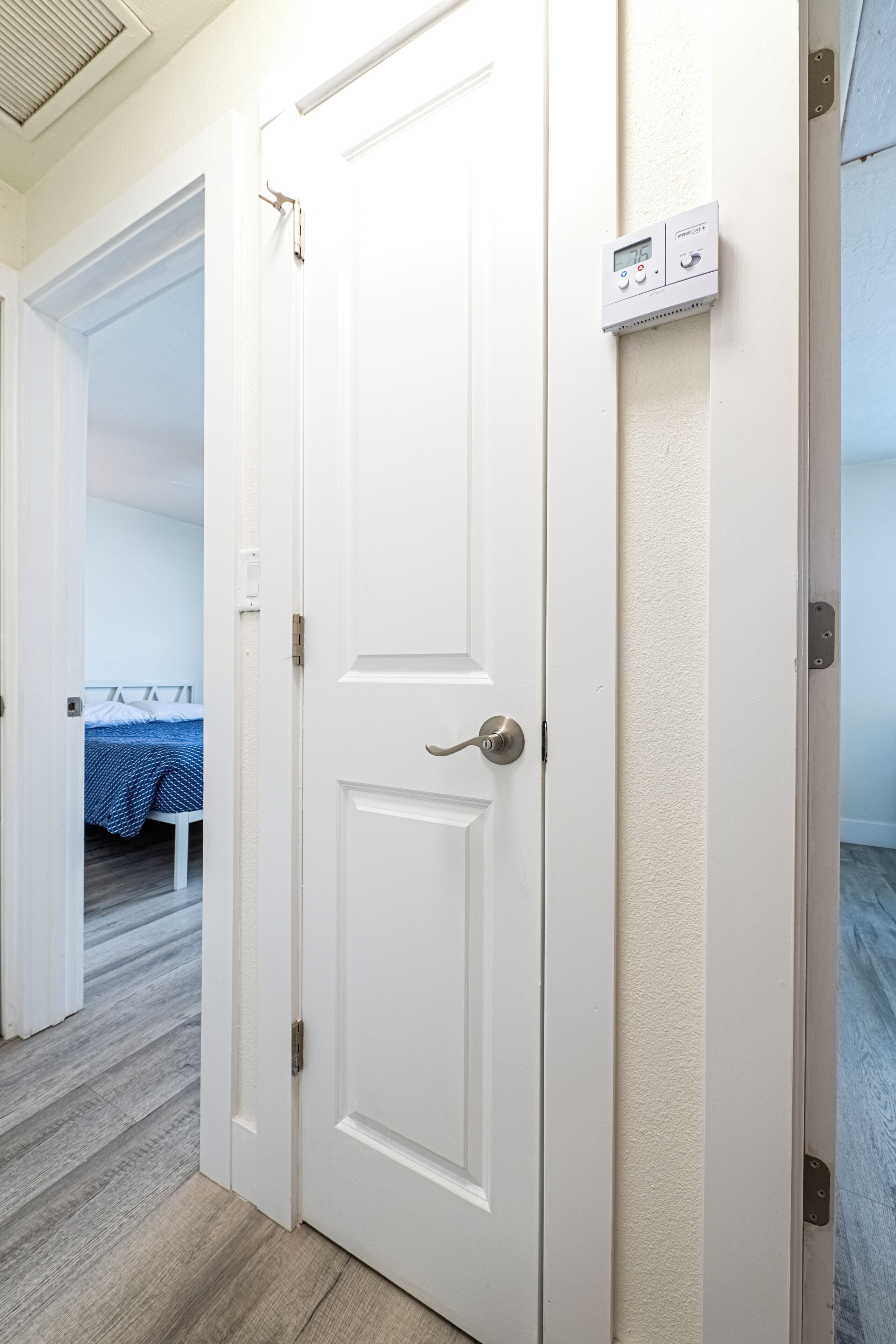 A white door with a digital thermostat and a lock.
