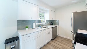 Una cocina moderna con armarios blancos, lavavajillas de acero inoxidable y un refrigerador negro.