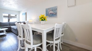 Un comedor con una mesa y sillas blancas, un jarrón de flores amarillas y un cuadro de un caballo en la pared.