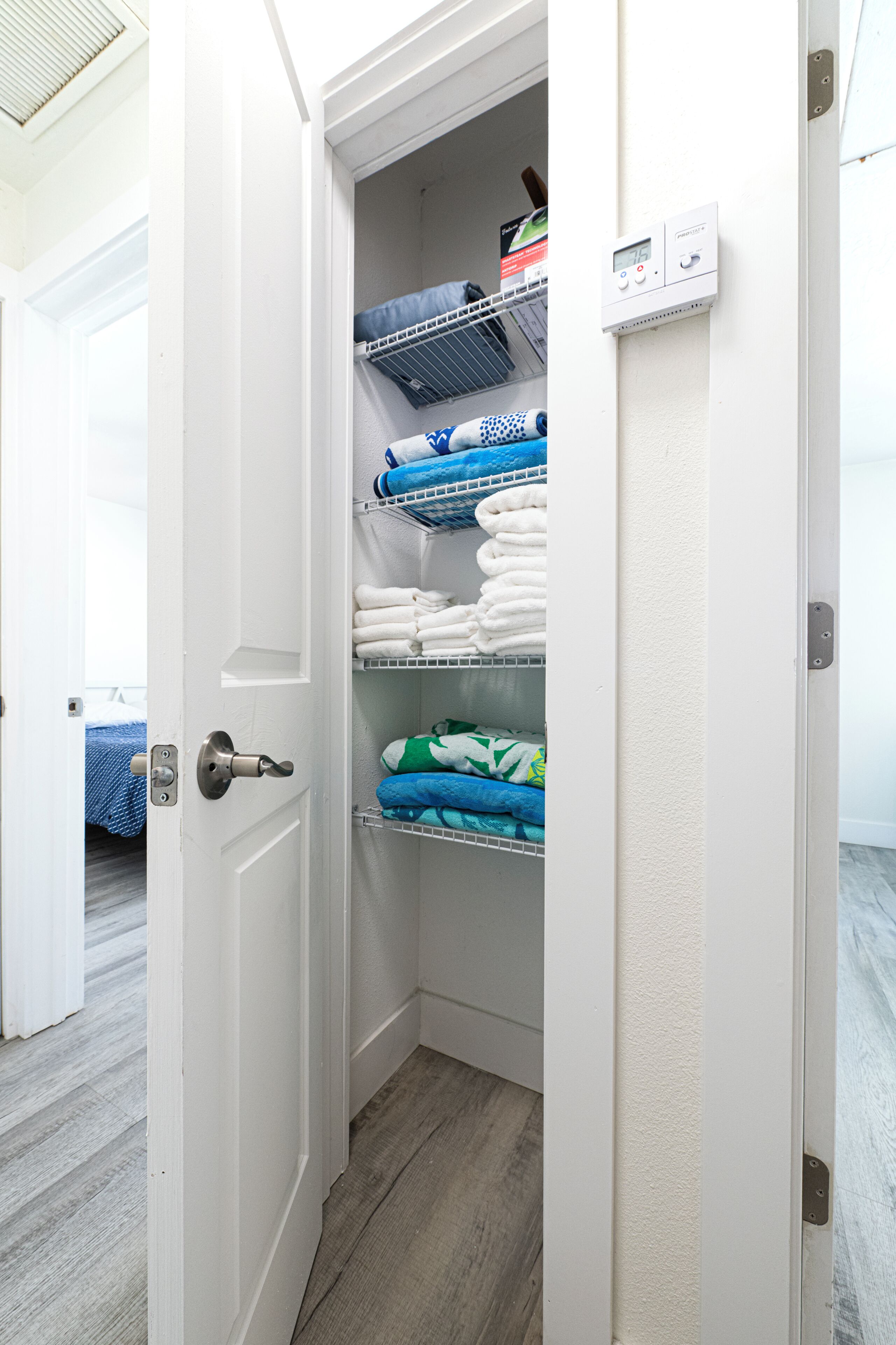 Een inloopkast met planken voor opgevouwen kleding en een bedieningspaneel aan de muur.