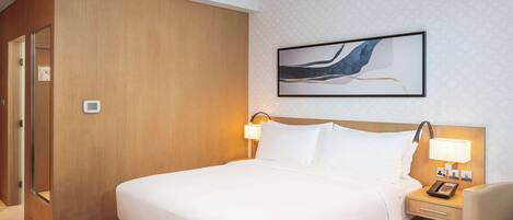 A hotel room with a large bed, bedside tables with lamps, a wooden wardrobe, and a framed abstract painting on the wall.