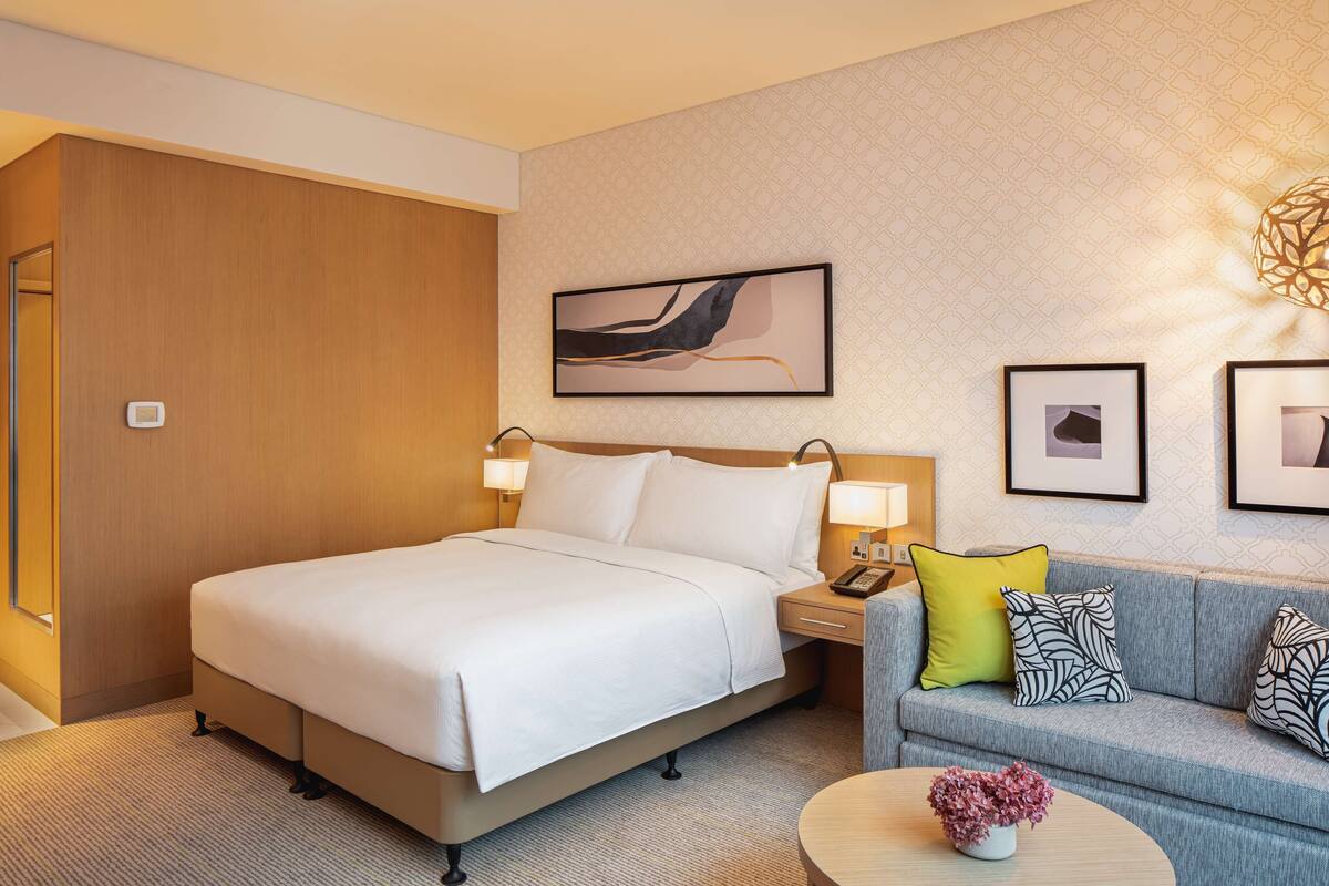 Une chambre d’hôtel avec un grand lit, un canapé, une table basse et un mur orné de tableaux.