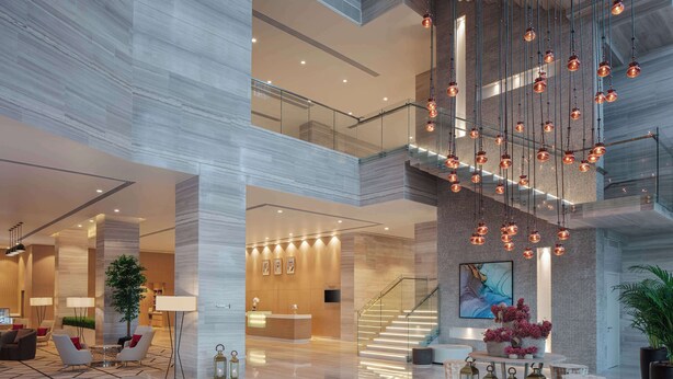 Een ruime lobby met een modern design, met een receptiebalie, een zithoek en een trap.