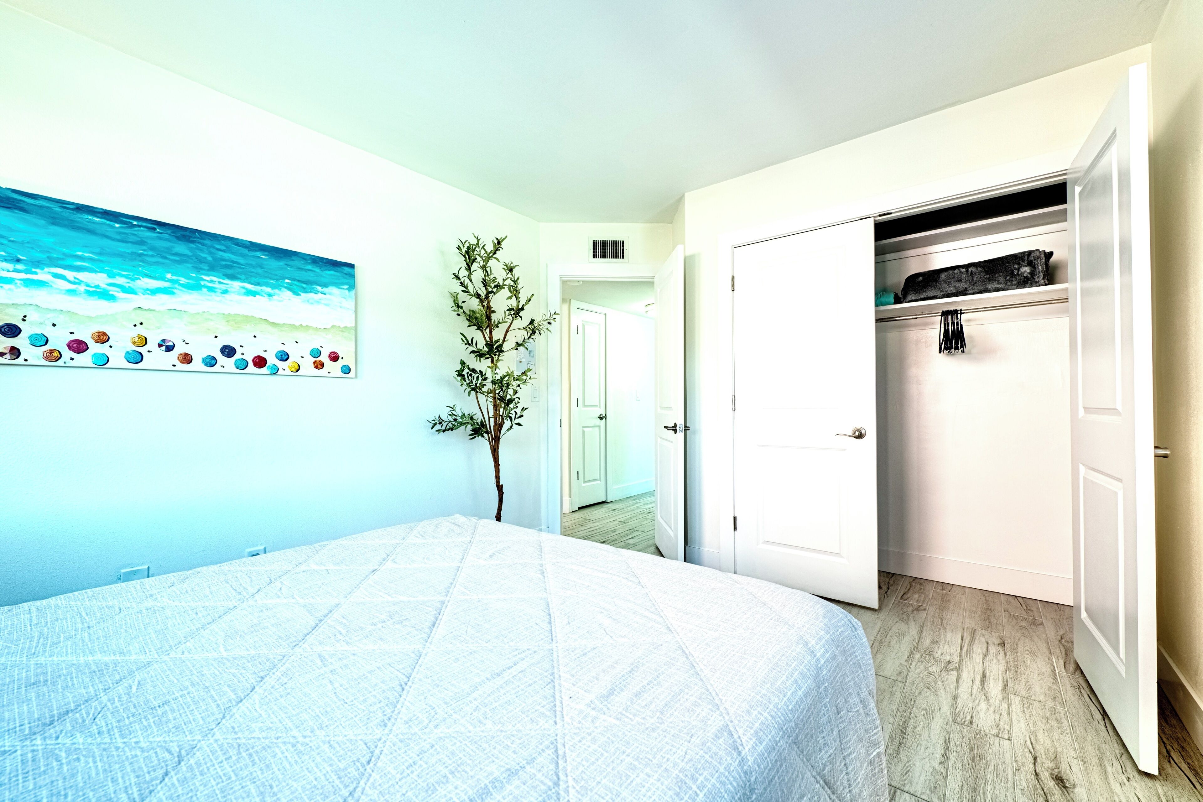 A bedroom with a bed, a closet, and a painting on the wall.