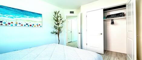 A bedroom with a bed, a closet, and a painting on the wall.