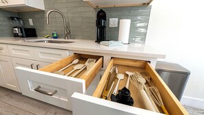 Una cucina moderna con mobili bianchi, un lavello in acciaio inossidabile e una macchina da caffè.
