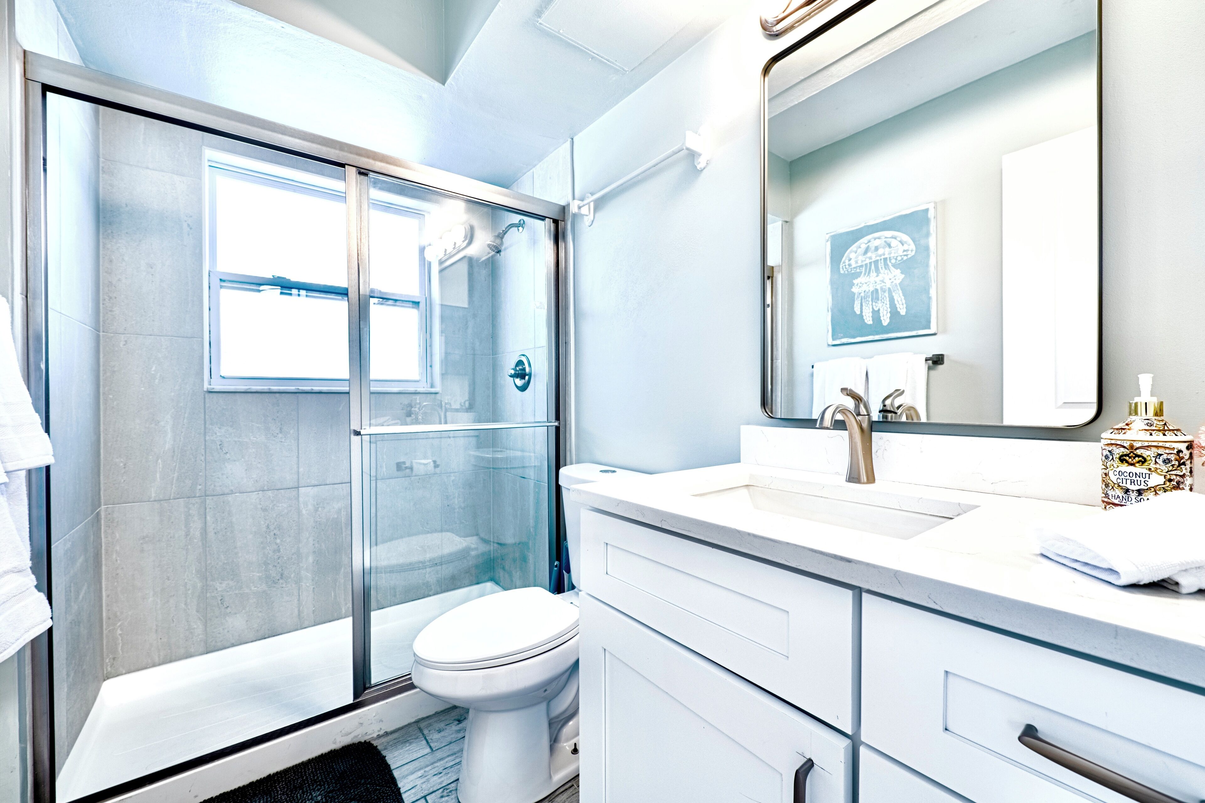 Une salle de bain moderne dotée d’une douche à parois de verre, de toilettes et d’un meuble-lavabo avec un grand miroir.