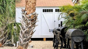 A backyard with a barbecue grill, a white shed, and a palm tree. - Cozy 2-bed, 1-bath second-floor unit minutes from Indian Rocks Beach. Sleeps 7 with full kitchen, WiFi, smart TV, beach gear, parking, and direct pool access. A bright, comfortable stay for families and groups (Indian Rocks Beach)