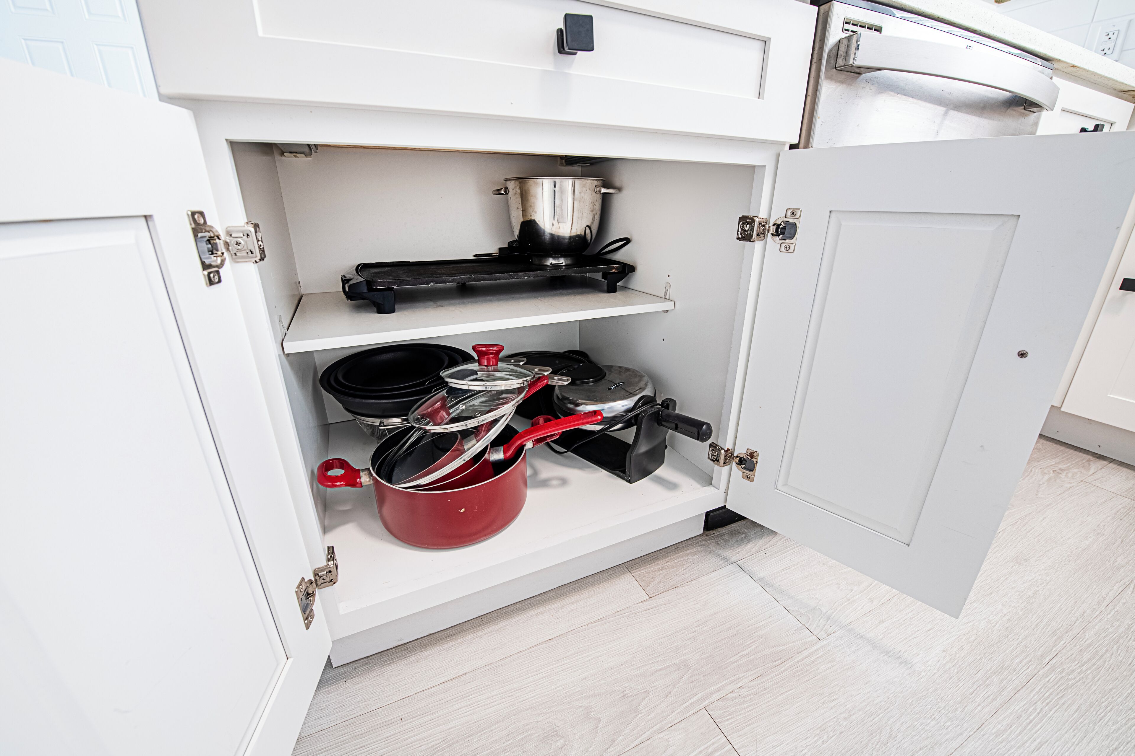 A kitchen with white cabinets, a stove, and a pot on the countertop.