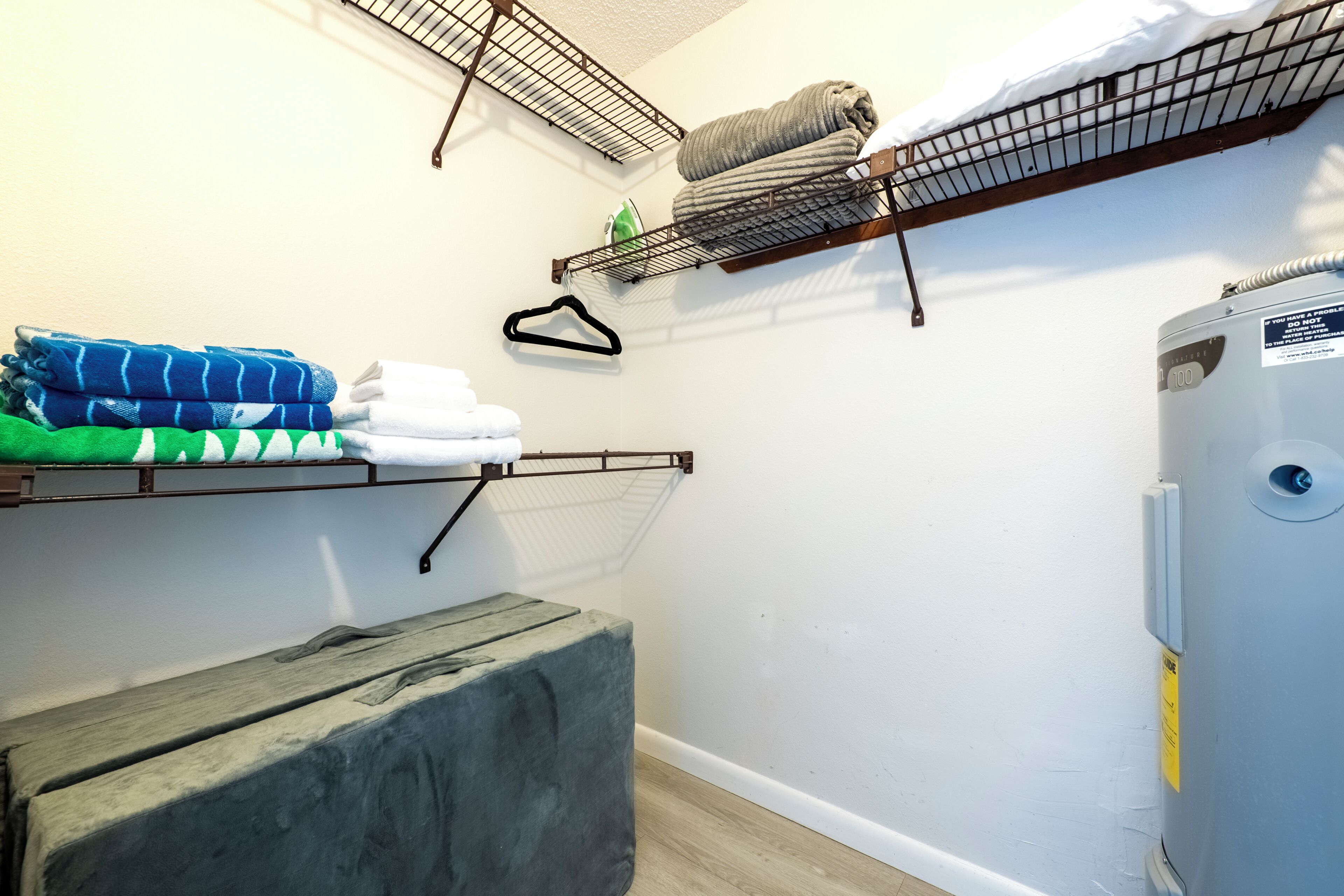A laundry area with metal shelves holding folded towels and a washing machine.
