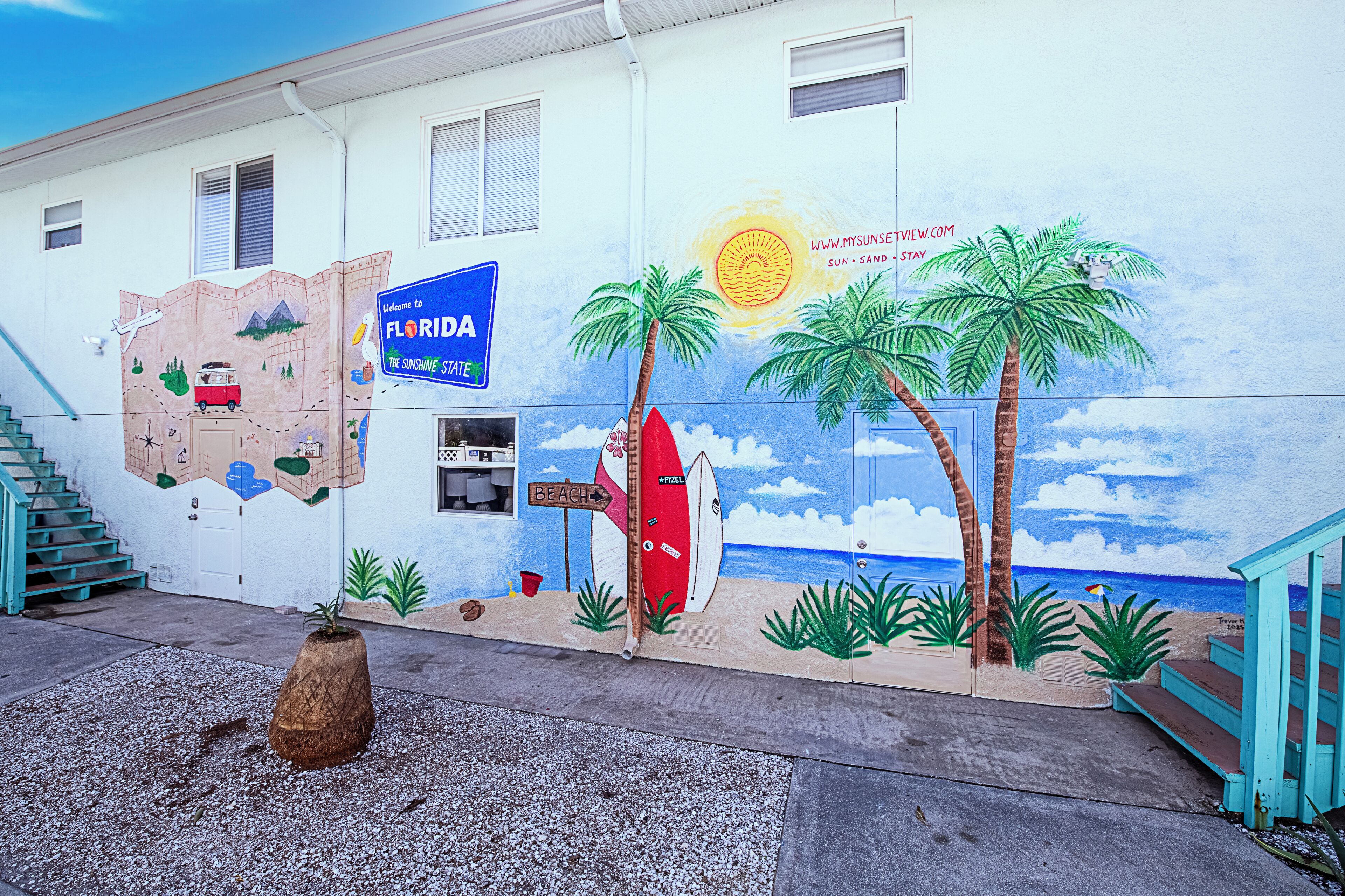 Een gebouw met een muurschildering van Florida, een strandbord en een surfplank.