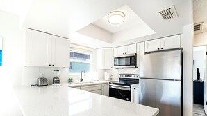 Una cucina moderna con mobili bianchi, elettrodomestici in acciaio inossidabile e una grande isola.