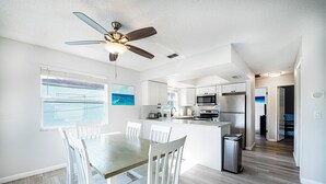Una cucina moderna con mobili bianchi, un'isola centrale e una ventola a soffitto.