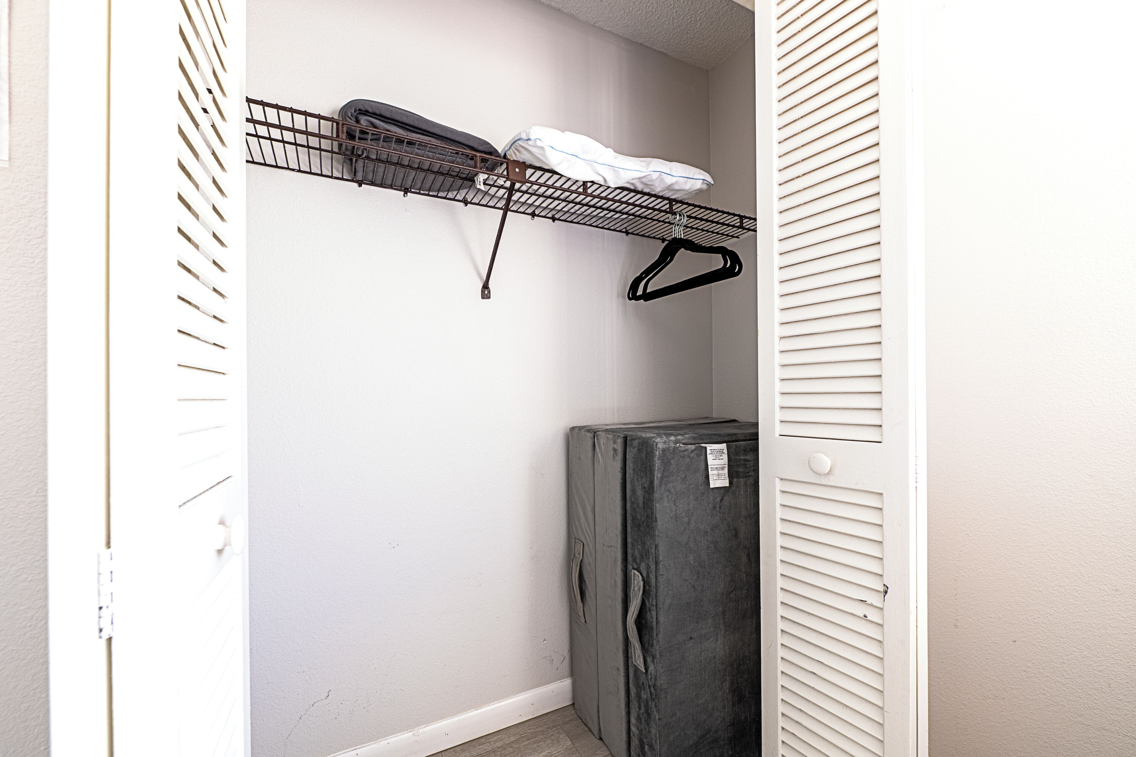 Un espacio de almacenamiento compacto con una estantería metálica, un refrigerador pequeño y una puerta blanca.