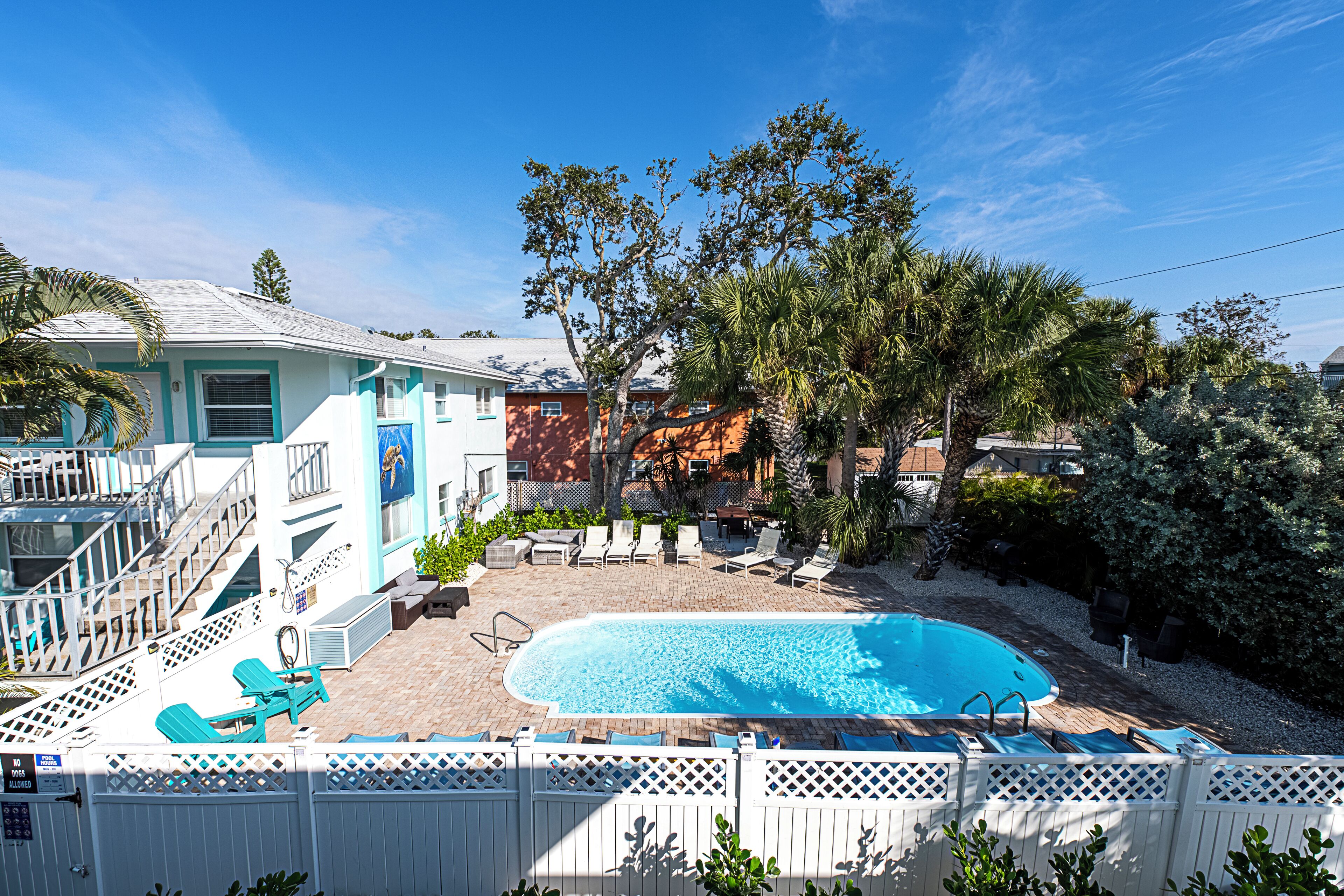 A backyard with a swimming pool, lounge chairs, and a fenced deck area.