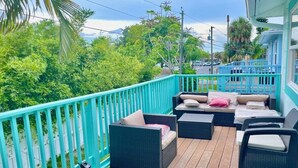 A covered outdoor deck with wicker furniture and a turquoise railing.